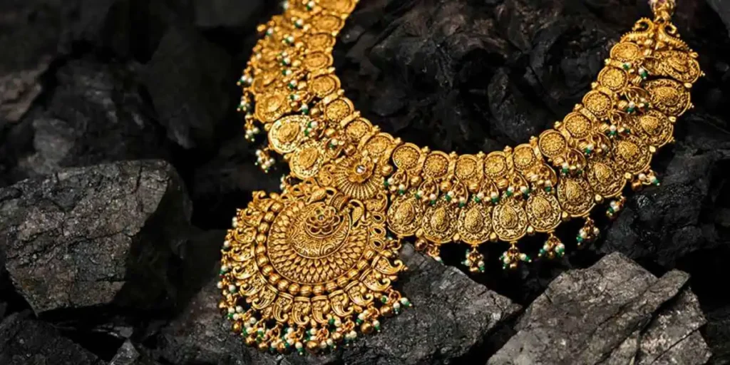 A gold necklace kept on the pieces of coal to display the beauty of it