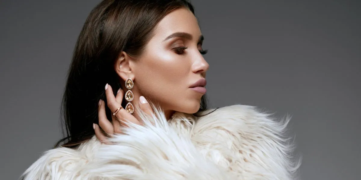 A women wear gold earring that is showing the winter jewelry trend